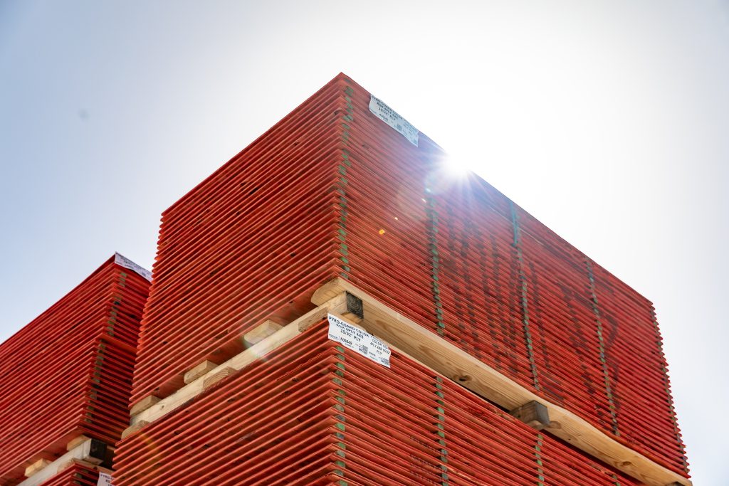 Fire-retardant-treated wood (FRTW) plywood stacks under a clear blue sky, highlighted by sunlight, ready for modern fire-safe construction projects.