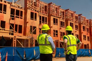 Two Hoover technical experts wearing safety vests and hard hats inspect a multi-story building framed with fire-retardant-treated wood