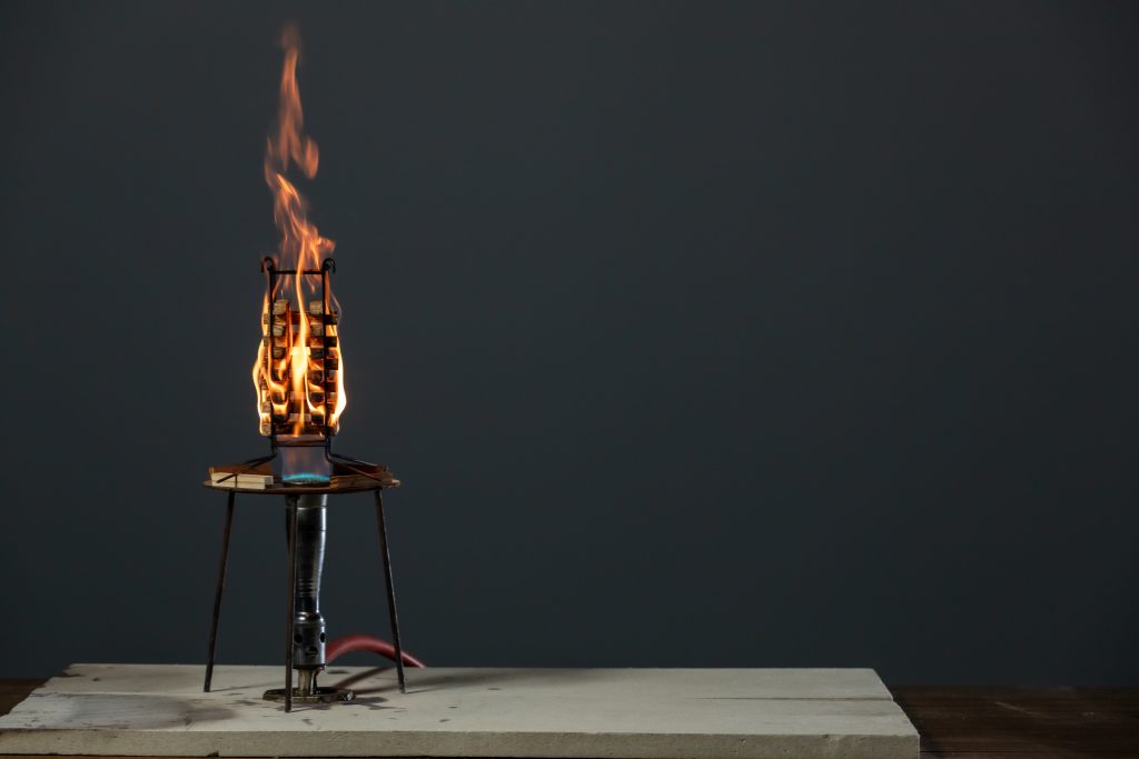Controlled flame test of stacked wood samples in a burn chamber, demonstrating fire-retardant-treated wood performance