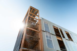 Multi-story building under construction with an exposed mass timber structural frame, illustrating fire-retardant-treated wood in design-forward architecture