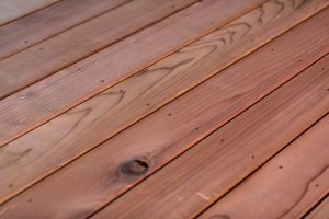Close-up of fire- retardant-treated redwood decking showing rich grain, a dark knot, and evenly spaced fasteners.